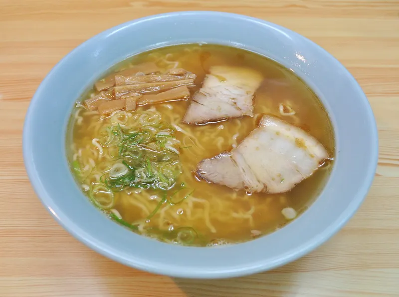 Bowl of Takayama ramen with thin noodles, chashu pork, bamboo shoots and spring onion in clear soy broth