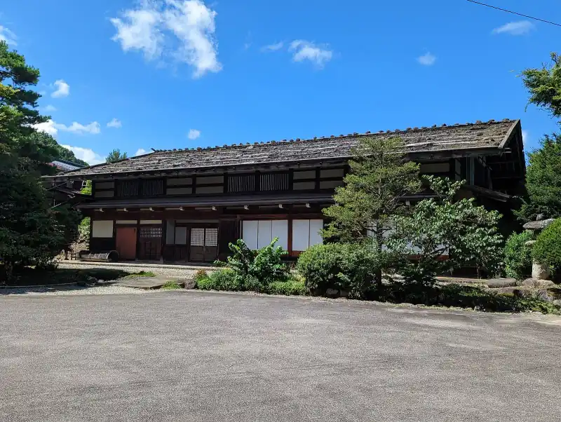 Arakawa family heritage farmhouse with a shingle roof in Takayama under a summer sky