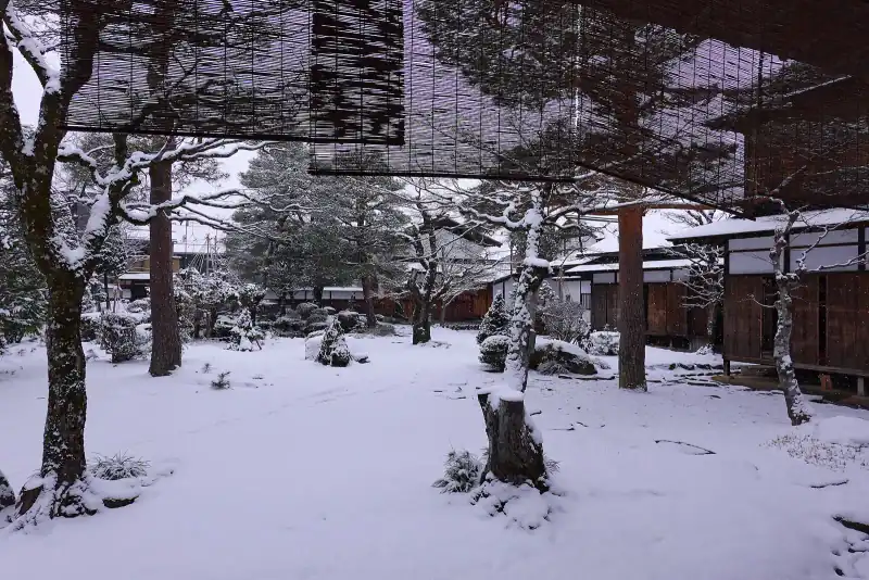 Snowy garden of Takayama Jinya seen from under the bamboo blinds of the eaves