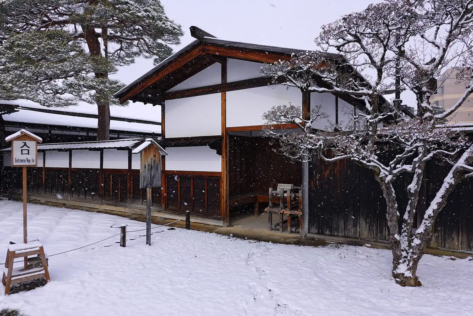 Snow-covered courtyard and white-walled hall at Takayama Jinya