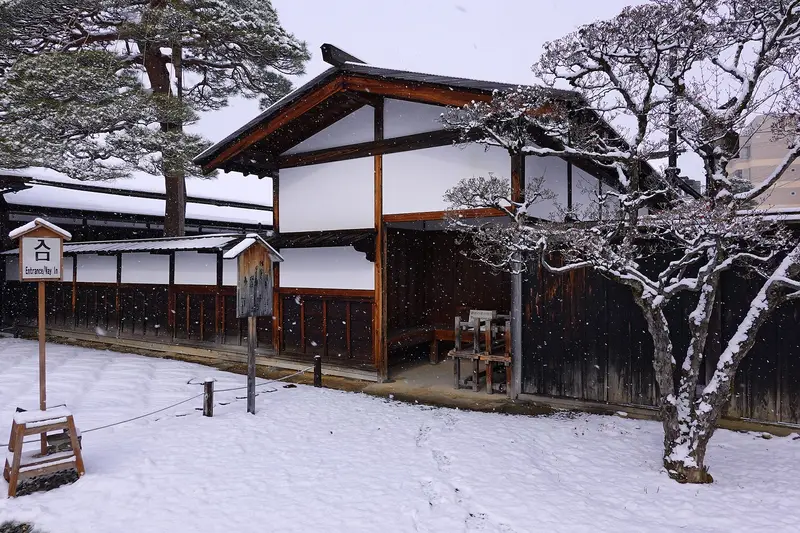 Snow-covered courtyard and white-walled hall at Takayama Jinya