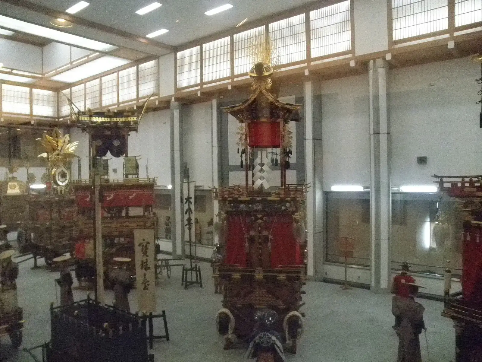 Festival floats with red curtains and gilded roofs lined up inside the Takayama Yatai Kaikan hall