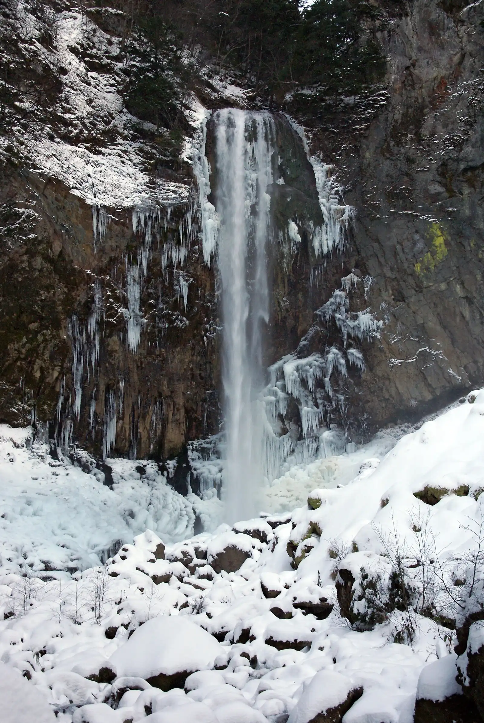 Hirayu Falls in winter, the water dropping past icicles onto snow-covered boulders