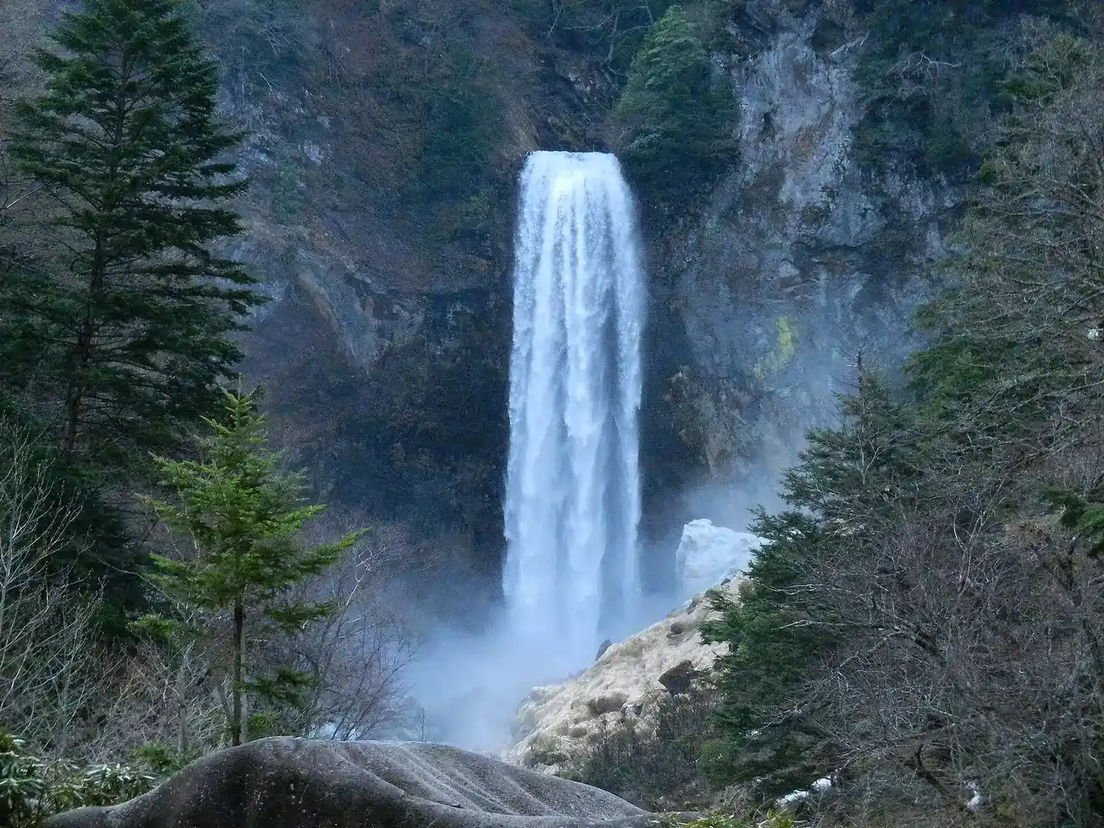 Hirayu Falls framed by fir trees, spray rising from the plunge pool