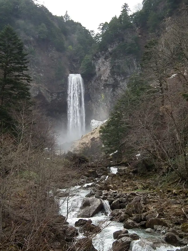 Hirayu Falls at the head of a rocky valley in early spring, the stream running towards the camera