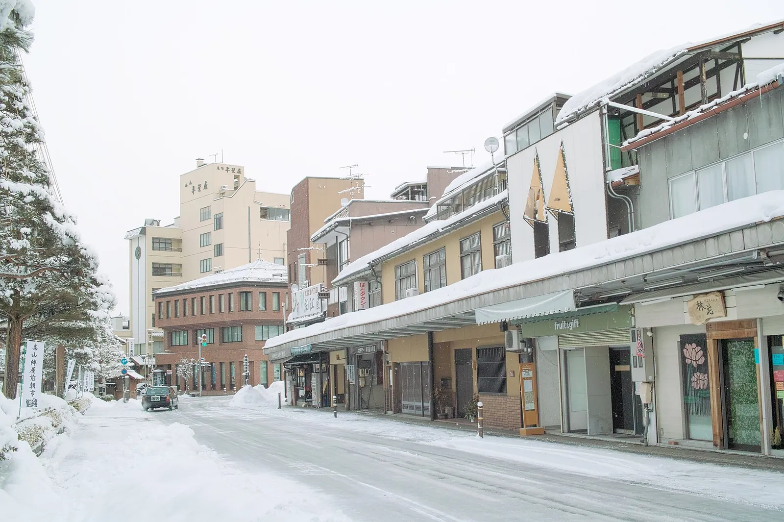 Snow-covered shopping street with covered walkways in Takayama's Hachikenmachi area in winter