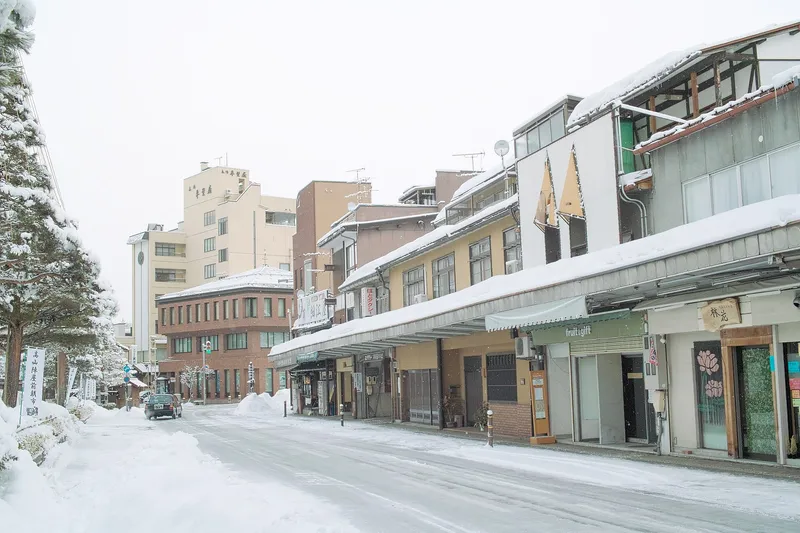 Snow-covered shopping street with covered walkways in Takayama's Hachikenmachi area in winter