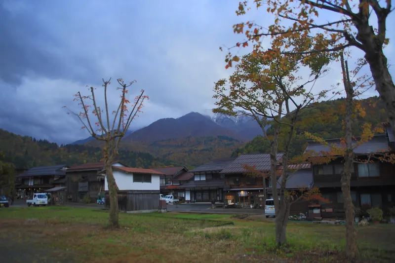 Shirakawa-go village houses below autumn hills and cloud-capped peaks